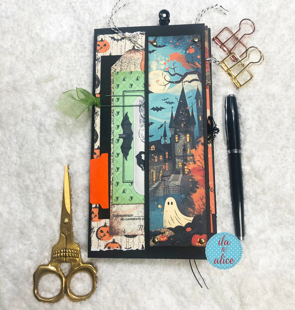 Halloween-themed folio with scissors, pen, and binder clips on a textured surface.
