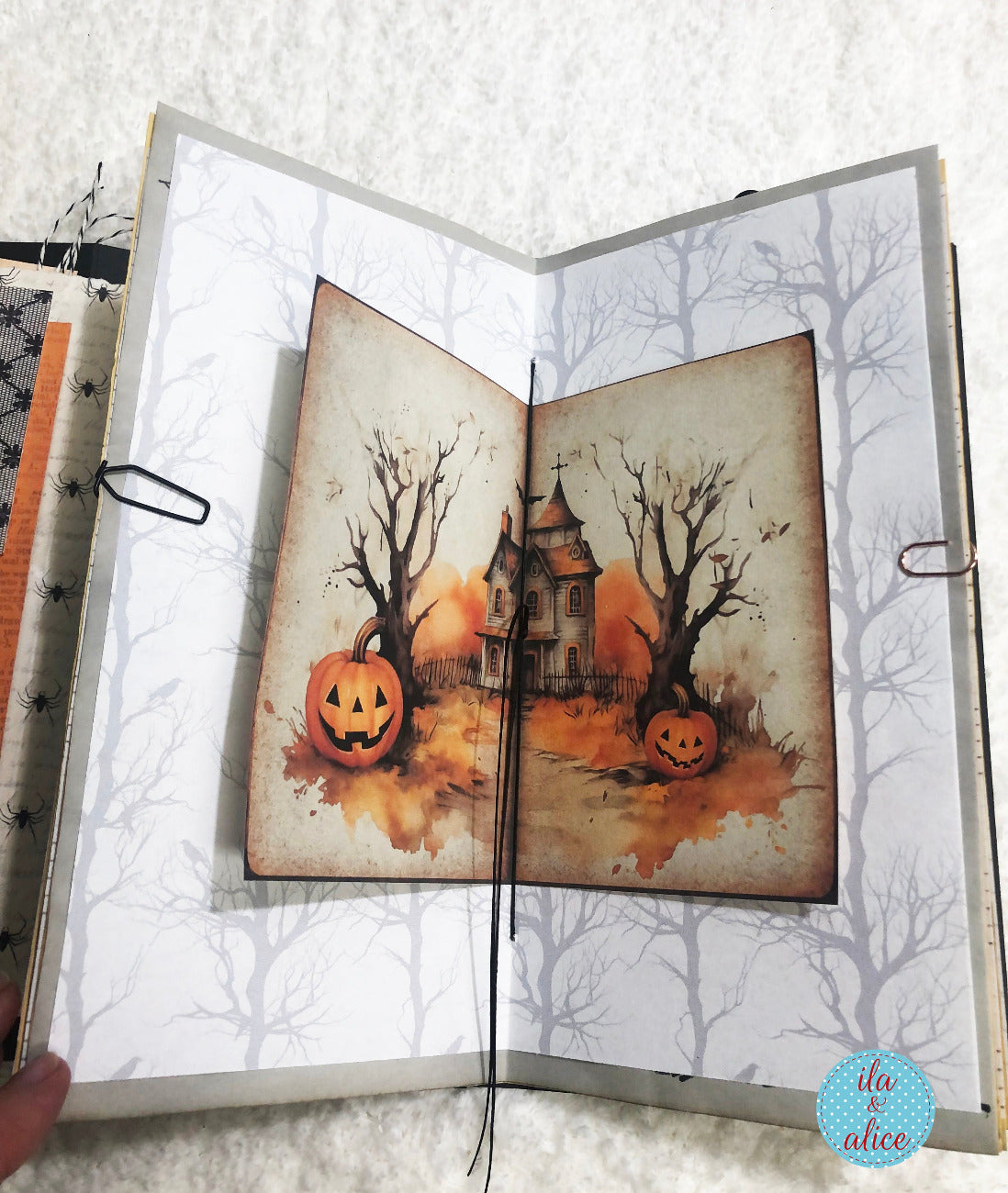 Open book with Halloween-themed illustration of a haunted house and pumpkin.