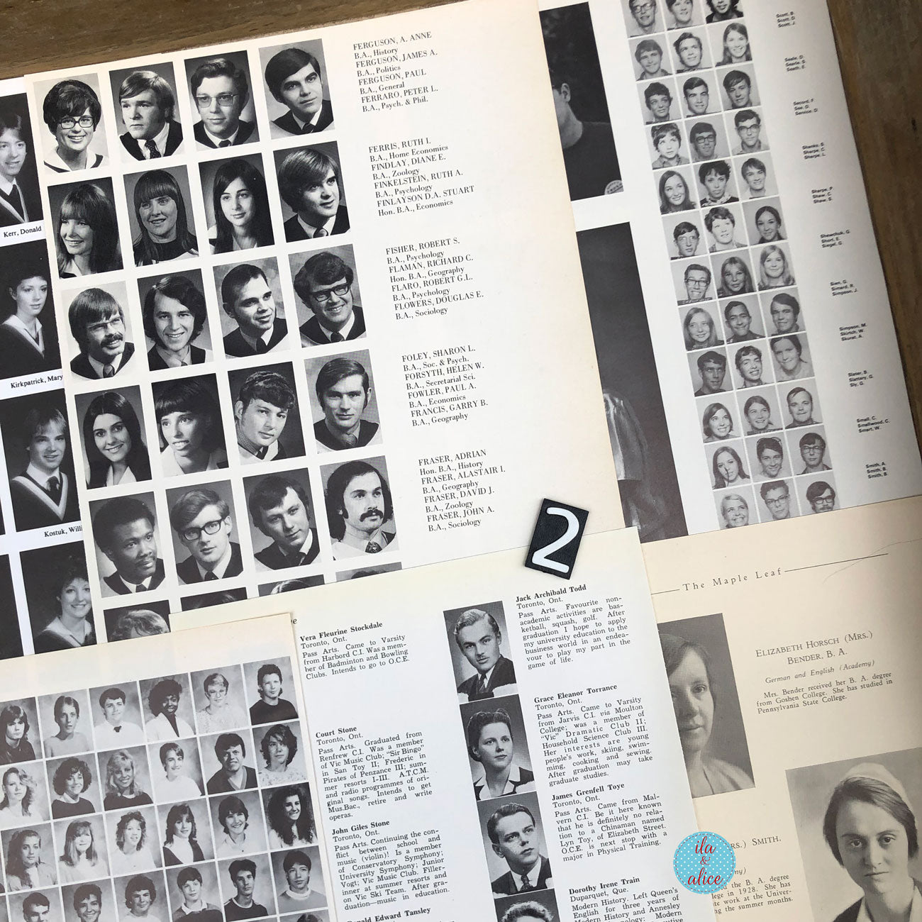 A close-up of printed alumni or yearbook pages laid out on a wooden surface, featuring rows of black-and-white portrait photos, names, and addresses, with a small black-and-white 'Z' card and a blue circular sticker.