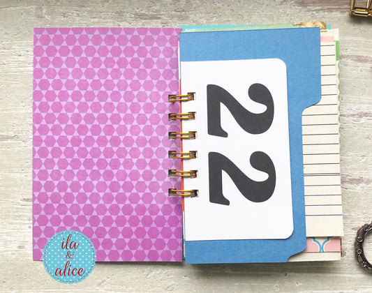 Planner with purple and blue cover on a wooden surface, featuring the brand 'ila & alice'.