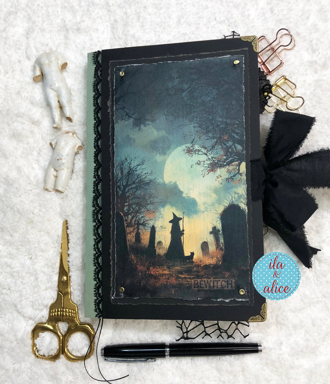 Handmade Eerie Halloween Gothic junk journal  with a Halloween-themed cover, surrounded by decorative items on a textured surface.
