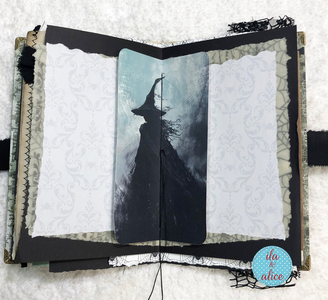 Handmade Eerie Halloween Gothic junk journal  w artistic depiction of a witch in a hat and cloak inside an open book with decorative elements.