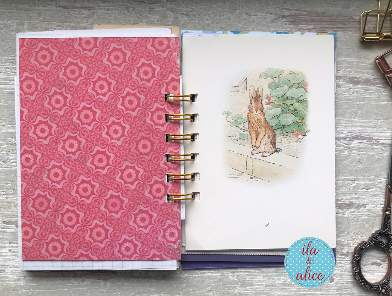 Planner with pink floral cover and rabbit illustration on a wooden surface, featuring 'fla & alice' branding.