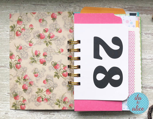 Planner with floral cover and a page displaying the number 28 on a wooden surface.