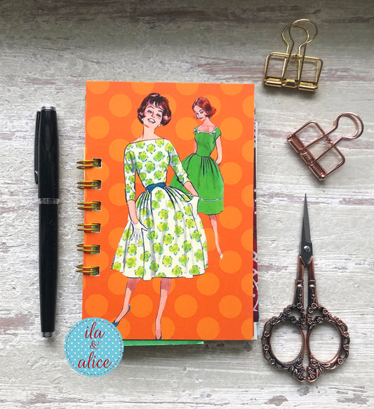 Mini handmade junk journal with vintage fashion illustration on orange polka dot background, spiral bound notebook