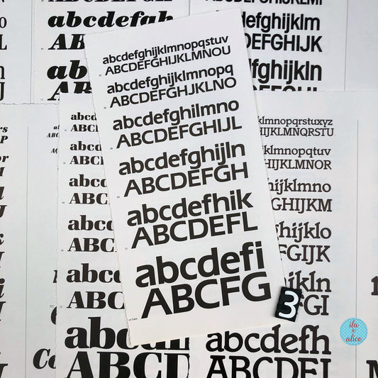 Several white book pages scattered on a white background, each printed with repeated black uppercase and lowercase alphabet lettering in varying font styles. A small circular logo in the bottom-right corner reads 'ila and alice'.