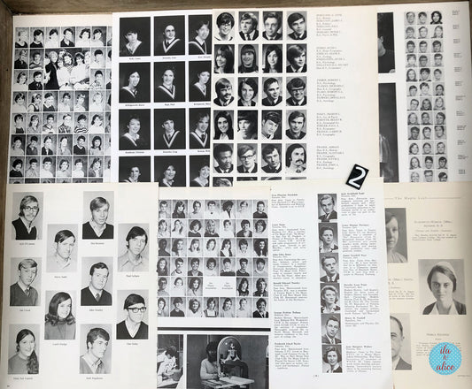 An open vintage yearbook or alumni magazine page spread showing numerous black-and-white portrait photos of graduates, names, addresses, and columns of text. The page is photographed from above on a wooden surface.
